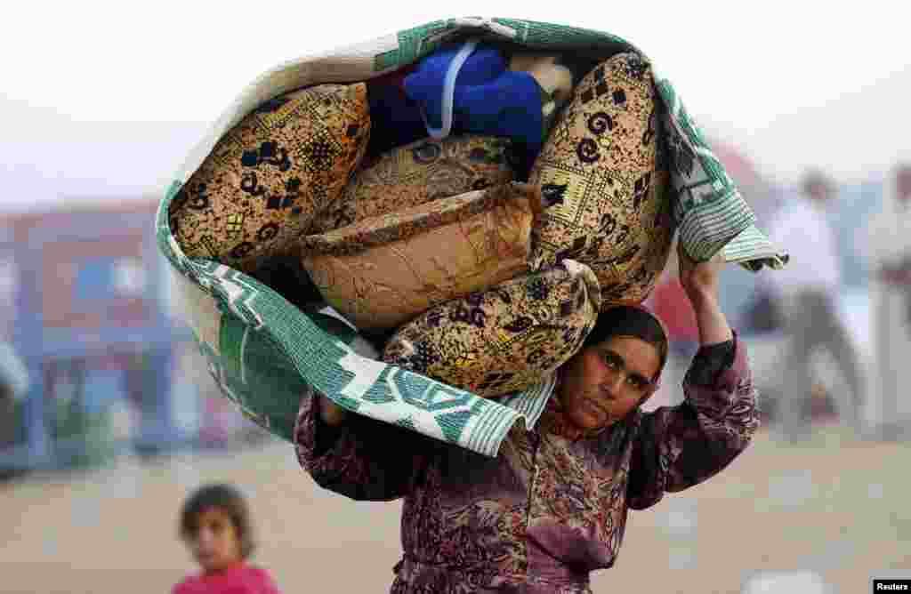 A Syrian Kurdish woman carries her belongings after crossing into Turkey near the southeastern town of Suruc in Sanliurfa province. 