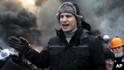 El líder opositor ucraniano Vitali Klitschko habla a manifestantes junto a barricadas en llamas en el centro de Kiev.