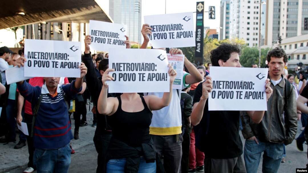 Residents hold up signs that read, "Metro workers: The people support you," outside Ana Rosa subway station during the fifth day of metro worker's strike in Sao Paulo, Brazil, June 9, 2014.