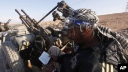 An anti-Gaddafi fighter reads the Koran at a checkpoint north of Bani Walid. (file photo)