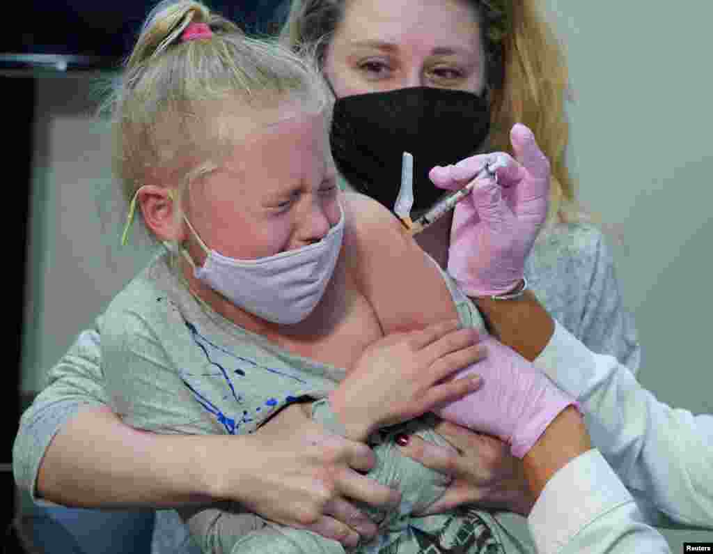 Emma Ingle, 7, sitting on her mother Kim Obert&#39;s lap, receives her first dose of the Pfizer-BioNTech coronavirus vaccine in Storrs, Connecticut, Nov. 3, 2021.