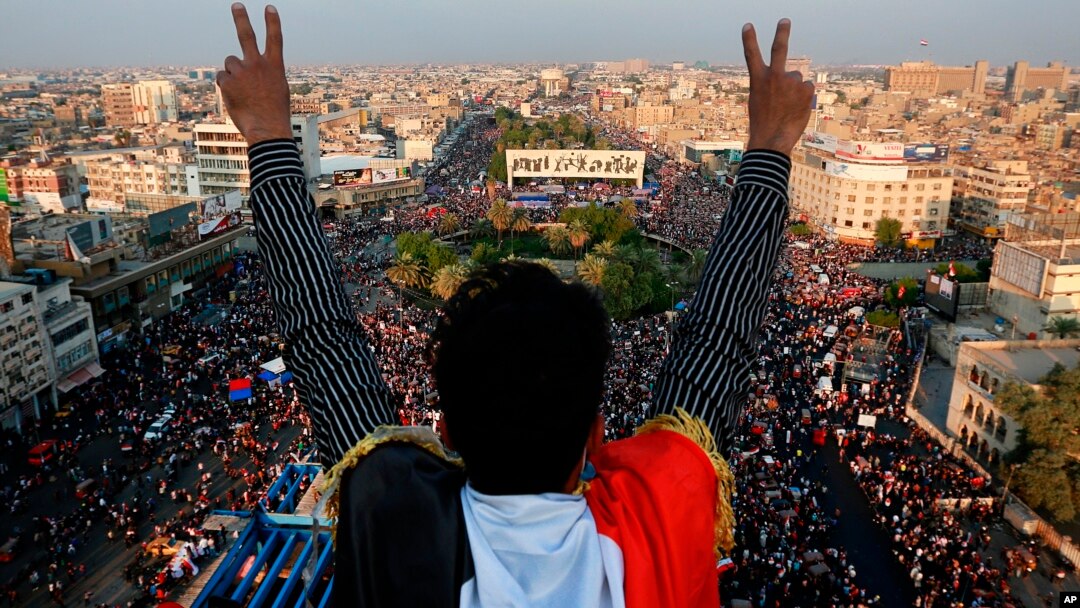Seorang pengunjuk rasa anti-pemerintah mengacungkan tanda kemenangan di hadapan massa yang berkumpul di Lapangan Tahrir di Baghdad, Irak, 31 Oktober 2019. 