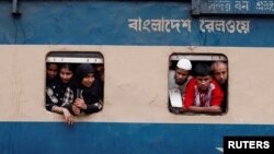 পবিত্র ঈদ-উল-ফিতর উদযাপন করার জন্য একটি উপচে পড়া যাত্রীবাহী ট্রেনের জানালায় দাঁড়িয়ে লোকজন গ্রামের বাড়িতে ছুটে যাচ্ছে। বাংলাদেশের রাজধানী ঢাকার একটি রেলওয়ে স্টেশন থেকে তোলা (ফাইল ছবি)। 