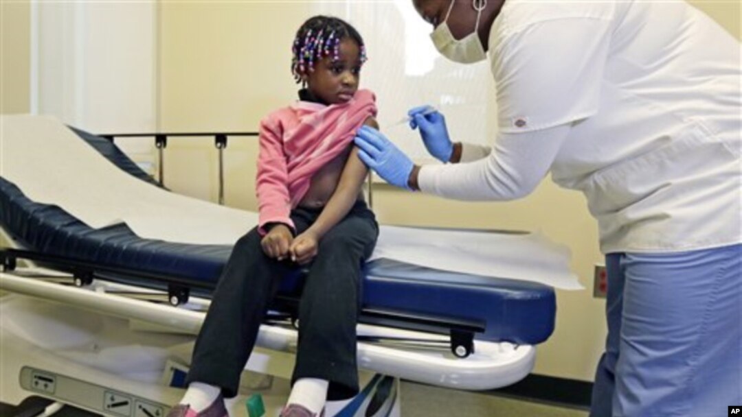Four-year-old Gabriella Diaz sits as registered nurse Charlene Luxcin (R) administers a flu shot at the Whittier Street Health Center in Boston, Massachusetts, January 9, 2013. Boston declared a public health emergency and the state reported 18 flu-relate