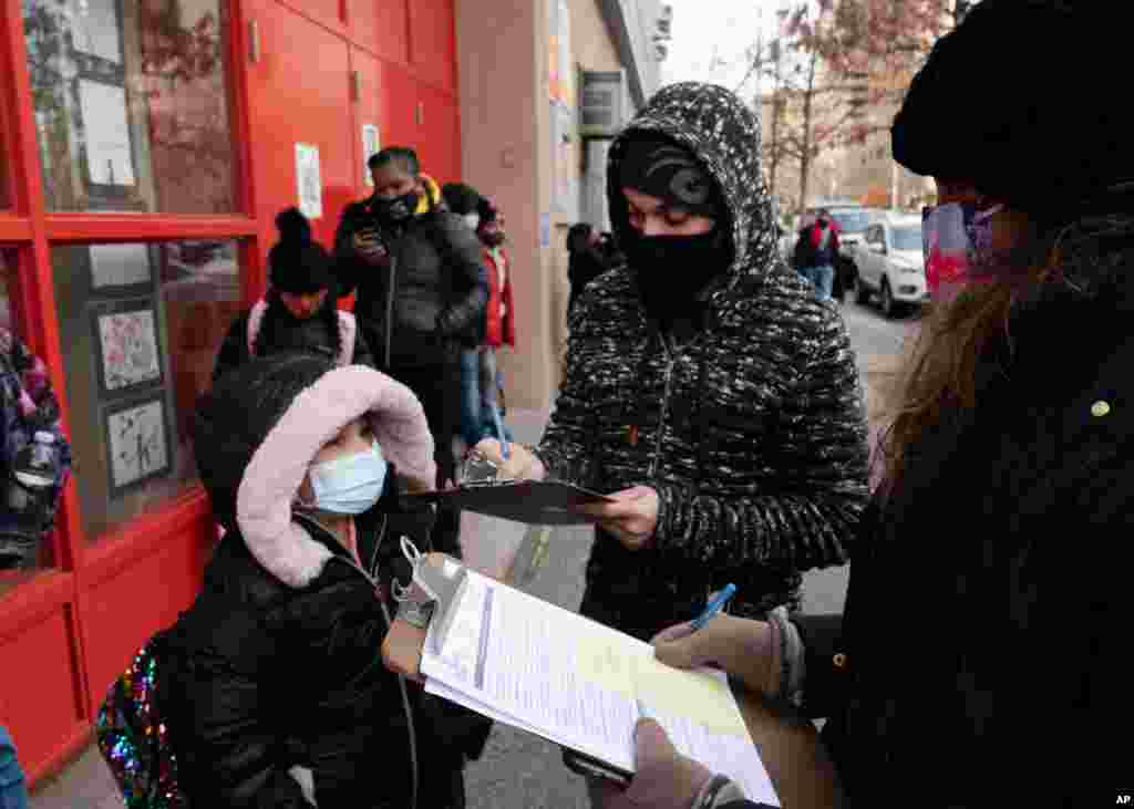 والدین این دختر در نیویورک فرم اجازه تست کووید۱۹ که به طور تصادفی از دانش آموزان گرفته می شود را پر می‌کنند 