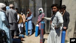 Men wait outside a privately owned oxygen factory to get their oxygen cylinders refilled, in Kabul, Afghanistan, June 19, 2021.
