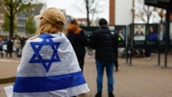 Seorang perempuan mengenakan bendera Israel berdiri di luar gedung di mana Wali Kota Amsterdam Femke Halsema menghadiri jumpa pers menyusul kekerasan yang menarget fans klub sepak bola Israel di Amsterdam, Belanda, Jumat, 8 November 2024. (Foto: Piroschka Van De Wouw/Reuters)
