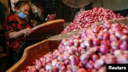 Seorang pedagang mengenakan masker wajah sedang memilah bawang di pasar tradisional di tengah pandemi virus corona (Covid-19) di Jakarta, 3 Agustus 2020. (Foto: Reuters)