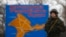 FILE - A Russian serviceman stands on duty near a map of the Crimea region near the city of Kerch, March 4, 2014.