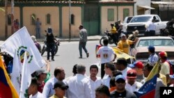 En esta fotografía difundida por la oficina de prensa de Juan Guaidó, un sujeto no identificado apunta con una pistola hacia un grupo de personas cuando el dirigente opositor, al centro con camisa azul claro, se reunía con partidarios en Barquisimeto, el sábado 29 de febrero.