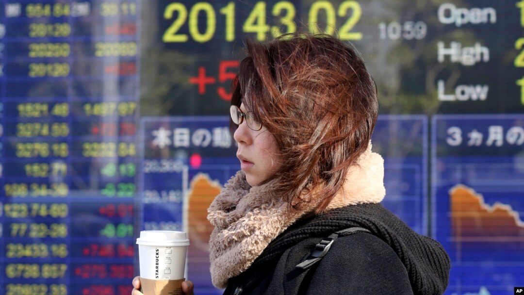 Seorang wanita berjalan melewati sebuah perusahaan sekuritas di Tokyo, Senin, 7 Januari 2019. (Foto: AP)