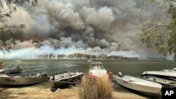 Kapal-kapal ditarik ke tepi danau saat asap tebal dan kebakaran hutan membumihanguskan kawasan di sekitar danau Conjola, Australia, Kamis, 2 Januari 2020.