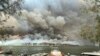 Boats are pulled ashore as smoke and wildfires rage behind Lake Conjola, Australia.