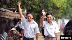 Reuters reporters Wa Lone and Kyaw Soe Oo gesture as they walk to Insein prison gate after being freed, after receiving a presidential pardon in Yangon, Myanmar, May 7, 2019. 