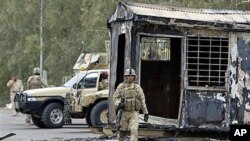 Iraqi army soldiers stand guard near burned trailers at Camp Ashraf, north of Baghdad, Iraq, April 2011 (file photo)