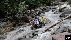 Regu penyelamat tengah membawa korban banjir yang melanda air terjun Dua Warna di Sibolangit, Sumatra Utara (16/5).