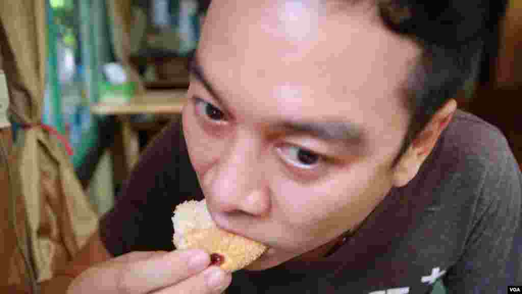 Customer Thanasith Ket-In enjoying his first snack of the old Portuguese pastry at Thanusingha Bakery. (Zinlat Aung for VOA News)