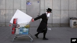 Seorang Yahudi ultra-Ortodoks menarik troli supermarket di jalan yang sepi setelah pemerintah menerapkan kebijakan menjaga jarak untuk mencegah penyebaran virus corona di Bnei Brak, Tel Aviv, Israel, 3 April 2020. 