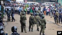 FILE - Ugandan army soldiers and police officers stand in front of a crowd during an opposition protest in Kampala, Uganda, Aug. 31, 2018.