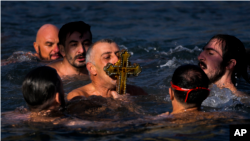 Católicos ortodoxos besan un crucifijo de madera recuperado en el Cuerno de Oro durante la ceremonia de Epifanía en Estambul, Turquía, el jueves 6 de enero de 2022. (Foto AP/Francisco Seco)