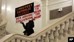 FILE - A rally participant holds up protest signs, Oct. 24, 2018, at the Capitol in Harrisburg, Pennsylvania. 