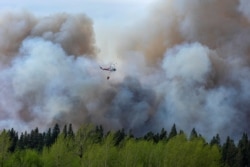 FILE - Water droppers battle an out of control forest fire after the city of Prince Albert declared a state of emergency over a fast-moving wildfire, prompting some residents to evacuate, in Prince Albert, Saskatchewan, Canada, May 18, 2021.