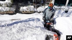 Un hombre despeja la nieve de una acera el domingo 30 de enero de 2022, en Scituate, Massachusetts, EE. UU.