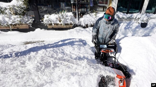 Un hombre despeja la nieve de una acera el domingo 30 de enero de 2022, en Scituate, Massachusetts, EE. UU.