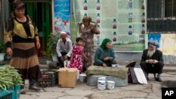FILE - In this photo taken July 17, 2014, Uighur residents gather at a road side stall in the city of Aksu in western China's Xinjiang province. 