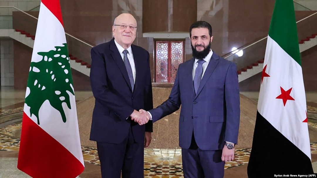 A handout picture released by the official Syrian Arab News Agency, shows Lebanon's Prime Minister Najib Mikati, left, shakes hands with Syria's new leader Ahmed al-Sharaa before their meeting in Damascus, Jan. 11, 2025.