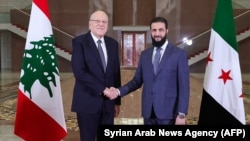 A handout picture released by the official Syrian Arab News Agency, shows Lebanon's Prime Minister Najib Mikati, left, shakes hands with Syria's new leader Ahmed al-Sharaa before their meeting in Damascus, Jan. 11, 2025.