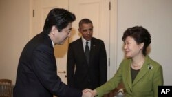 Presiden Korea Selatan Park Geun-hye (kanan), berjabat tangan dengan Perdana Menteri Jepang Shinzo Abe, disaksikan oleh Presiden AS Barack Obama sebelum pertemuan trilateral di Den Haag (25/3). (AP/Yonhap, Do Kwang-hwan) 