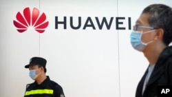 Seorang petugas keamanan tampak berjaga di dekat stan Huawei dalam sebuah ekshibisi di Beijing, China, pada 28 Spetember 2021. (Foto: AP/Mark Schiefelbein)