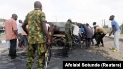 Des militaires se joignent à des civils pour retirer un générateur électrique brûlé d'une rue à Ikeja, dans l'État de Lagos au Nigeria, le 23 octobre 2020. 