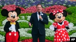 Joe Schott, center, president and general manager of Shanghai Disney Resort, speaks, along with Mickey and Minnie Mouse, during its reopening ceremony after the coronavirus closure in Shanghai, China, Monday, May 11, 2020. Visits will be limited…