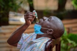 A man with a cough but who had not been tested for the coronavirus uses COVIDEX, a locally-made herbal medicine approved by the government for use as a supportive treatment for viral infections, in Kampala, Uganda, July 6, 2021.