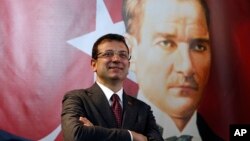 Ekrem Imamoglu berpose dengan latar belakang gambar pendiri Turki Mustafa Kemal Ataturk di Istanbul, 4 April 2019. 