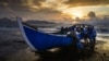 Fishermen push their boat onto the shore upon returning from the sea as the sun sets in Banda Aceh, Indonesia.