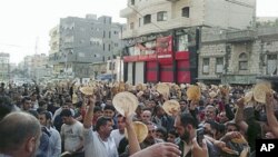 In this citizen journalism image made on a mobile phone, Syrian men carry bread loaves during a protest against Syrian President Bashar Assad's regime, in the coastal town of Banias, Syria, May 3, 2011