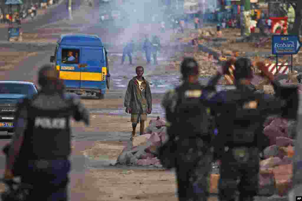 Mtu anaewaangalia polisi wa kupambana na ghasia katika mtaa wa Matete ngome ya kiongozi wa upinzani Tshisekedi mjini Kinshasa baada ya kuzuka ghasia kufuatia kutangazwa matokeo ya uchaguzi.