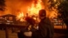 People watch as the Eaton Fire engulfs a structure in Altadena, California, Jan. 8, 2025.