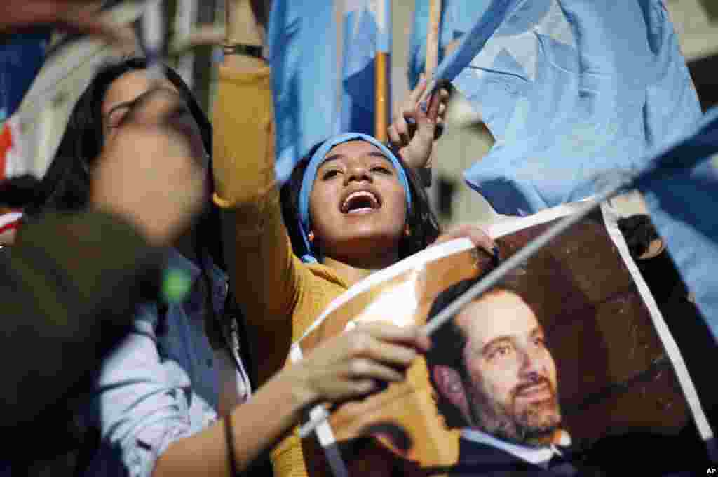 A girl chants slogans as she holds a picture of Lebanese Prime Minister Saad Hariri outside his residence in Beirut. Hariri returned to Lebanon a day earlier and in a surprise decision, said he was putting his resignation on hold responding to a request from the president to give more time to consultations.