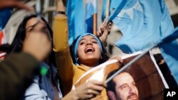 Seorang anak perempuan menyerukan slogan-slogan sambil memegang gambar Perdana Menteri Lebanon, Saad al-Hariri, di luar kediamannya di Beirut, Lebanon, Rabu, 22 November 2017. 