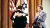 (FILES) Egyptian President Anwar al-Sadat (back to camera) and Israeli Premier Menachem Begin embrace each other, on September 17, 1978, after signing a peace agreement in the East Room of the White House in Washington, DC, as US President Jimmy Carter lo