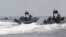 FILE - U.S. and Philippine Navy servicemen aboard patrol boats conduct a boat manoeuvre exercise past a fishing boat during a joint annual military exercise called "Carat" at the former U.S. military base Sangley Point in Cavite city, west of Manila, June