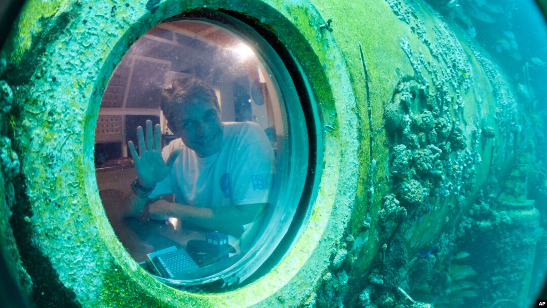 Fabien Cousteau waves from inside Aquarius Reef Base, a laboratory 63 feet below the surface in the waters off Key Largo, in the Florida Keys National Marine Sanctuary, June 24, 2014.