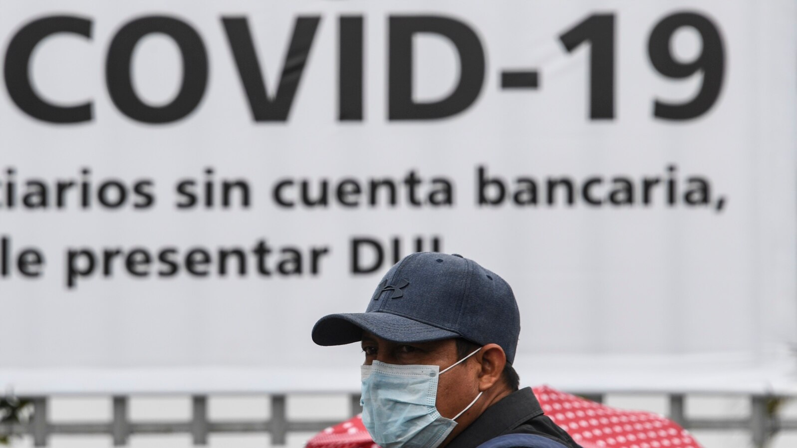 FILE - A man wears a face mask against the spread of the new coronavirus (COVID-19) as he waits to enter a bank to receive a $300 USD bonus, granted by the government for vulnerable people, in Santa Tecla, El Salvador, April 3, 2020.