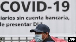 FILE - A man wears a face mask against the spread of the new coronavirus (COVID-19) as he waits to enter a bank to receive a $300 USD bonus, granted by the government for vulnerable people, in Santa Tecla, El Salvador, April 3, 2020.
