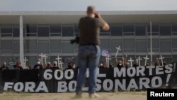 Demonstrators hold a banner and crosses during a protest to pay tribute to Brazil's 600,000 COVID-19 deaths and against Brazil's President Jair Bolsonaro's handling of the coronavirus disease pandemic, in Brasilia, Brazil, October 8, 2021. 