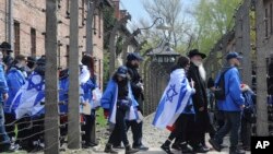 Participants of the yearly March of the Living walk through a barbed wire fence in the former German Nazi Death Camp Auschwitz-Birkenau, in Oswiecim, Poland, April 24, 2017. 